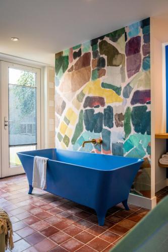 a blue tub in a bathroom with a stone wall at MUZE Hotel Utrecht in Utrecht
