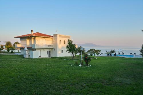 a house in a grassy field with a view of the water at Grand Villa Maronia in Platanitis Rodopis