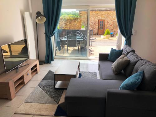 un salon avec un canapé et une télévision dans l'établissement Maison proche Auray, Carnac, Quiberon et littoral, à Locoal-Mendon