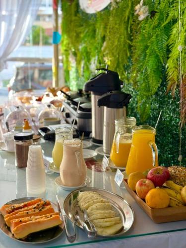a table topped with plates of food and orange juice at Pousada La Acolhida in Cabo Frio