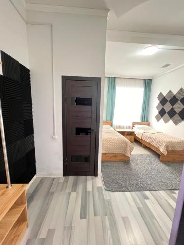 a bedroom with two beds and a door at Sayak hostel in Karakol