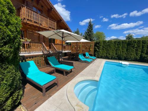 a pool with chairs and an umbrella next to a house at gîte de charme avec piscine et sauna in Le Thillot