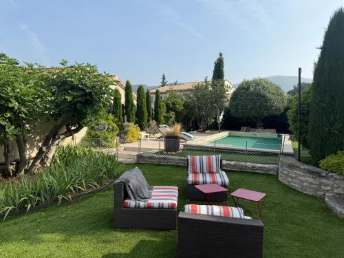 - un jardin avec deux chaises, une table et une piscine dans l'établissement Cabanon Lourmarin, à Lourmarin