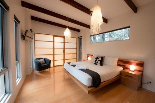 a bedroom with a bed and a chair in it at Stylish Dairy Cottage by the Sea- Romantic Luxury in Port Elliot