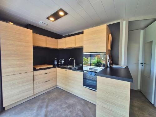 une cuisine avec des armoires en bois et un comptoir noir dans l'établissement Friendly Cottage - 2 chambres, jardin, à 5 minutes de la plage, à Agde