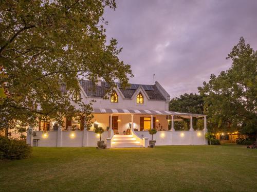 a white house with lights on the front yard at Caledon Grace Guesthouse in Caledon