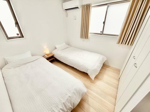 two beds in a room with two windows at ZZOKIAI紫葉 30-second walk to the seaside! You can see the sea from every floor! 4LDK maximun 10 people! in Itoman