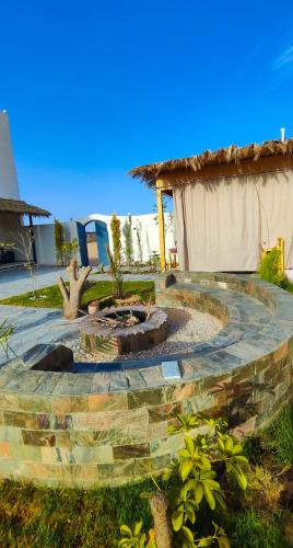 a stone patio with a fire pit in a yard at Laila's Home in Siwa