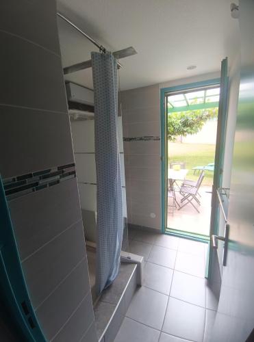 une salle de bain avec une porte coulissante en verre et un patio dans l'établissement Maisonnette Topaze bleu, à Argelès-sur-Mer