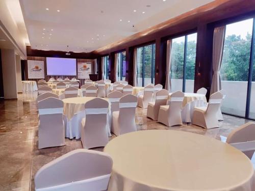 a room with tables and white chairs and a screen at Sea Shell Coral Cove in Port Blair