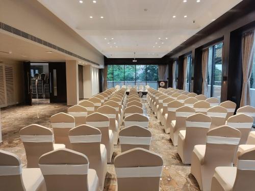 an empty room with white chairs and tables and windows at Sea Shell Coral Cove in Port Blair