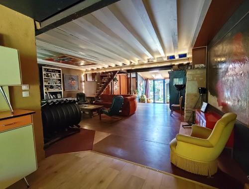 un salon avec une chaise jaune et un canapé dans l'établissement Maison d'artiste atypique en bordure de forêt, à Cellefrouin