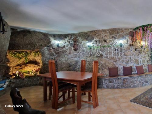 a table and chairs in a room with a stone wall at Quinta de S. Vicente 317 in Vila Nova de Famalicão