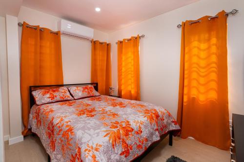 a bedroom with an orange curtains and a bed at Xoop Homes - Ixora #1 in Saint Johnʼs