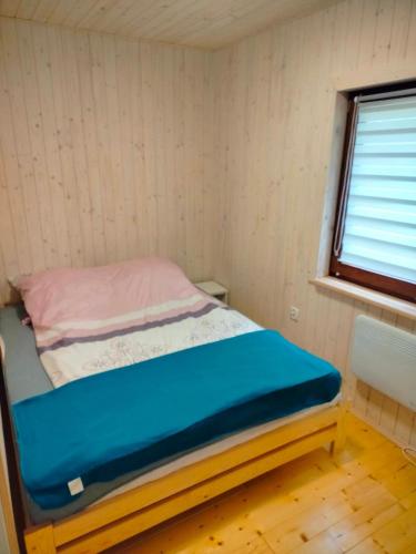 a small bed in a room with a window at Domek całoroczny in Buda Ruska