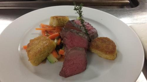 a white plate with a piece of meat and vegetables at Hotel Wieslhof in Collepietra