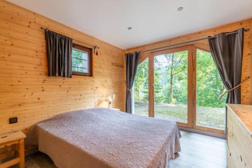une chambre avec un lit et une grande fenêtre dans l'établissement Chalet, Terrasse, Calme & Nature, à Saint-Jean-de-Sixt