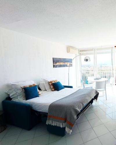 une chambre avec un grand lit avec des oreillers bleus dans l'établissement studio cosy vue mer, à Patrimonio