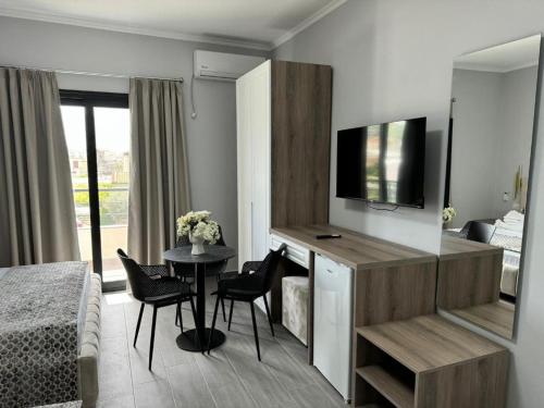a room with a bed and a desk with a television at Hotel 4Palmat in Orikum
