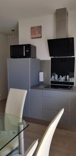 une cuisine avec une table en verre et des chaises blanches dans l'établissement Le MINOU, à Roquebrune-Cap-Martin