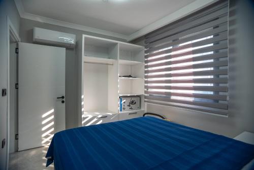a bedroom with a blue bed and a window at Sürer Apart Altınkum in Didim