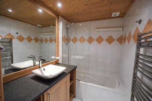 une salle de bain avec un lavabo et une baignoire dans l'établissement La Croix des Vallées - Proche des pistes des Ménuires, aux Menuires