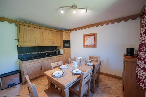 une cuisine avec une table en bois avec des chaises et un plateau de table dans l'établissement La Croix des Vallées - Proche des pistes des Ménuires, aux Menuires