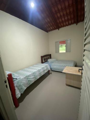 a room with two beds and a table in it at Rancho Pé de Serra in Manhã