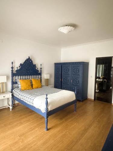 a bedroom with a blue bed with yellow pillows at Offshore Rustic House in Peniche