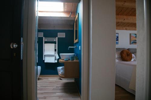 bagno con pareti blu, lavandino e servizi igienici di Fortaleza Charme House a Siracusa