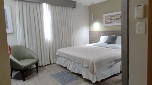 a hotel room with a bed and a chair at STOP Mar Suite Privada - NI in Nova Iguaçu