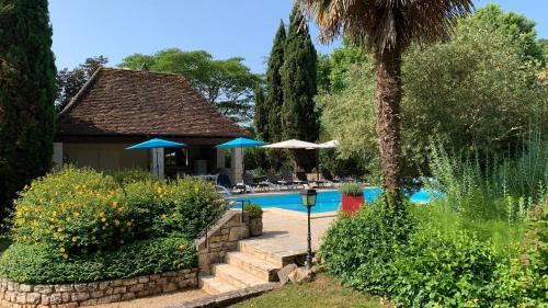 une piscine avec des parasols et une maison dans l'établissement Le Moulin du Boisset, à Saint-Denis-lès-Martel