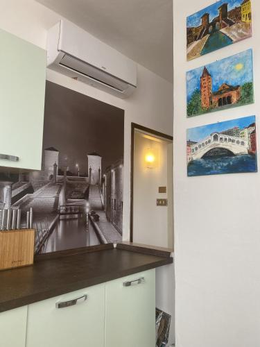 a kitchen with white cabinets and a painting on the wall at Casa Blu di Pomposa Vista Mare in Lido di Pomposa