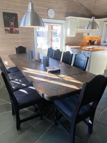 a large wooden table in a kitchen with chairs at Bjørnebuhytten, Geilo, 13 sengeplasser med privat Jacuzzi og el-bil-lading in Geilo