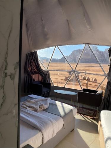 a bedroom with a bed and a view of the desert at Star Wars luxury camp in Wadi Rum