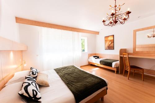 a hotel room with two beds and a chandelier at Hotel Arena le Refuge in Corte