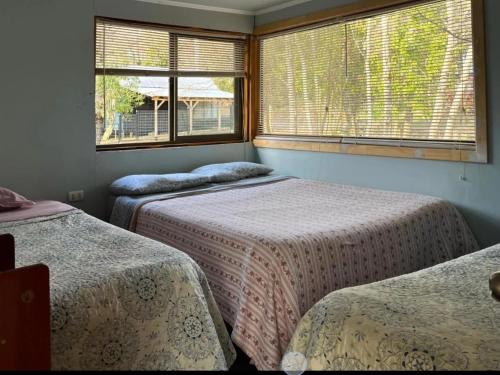 a room with two beds and two windows at Daben Recinto Ñuble camino Termas de Chillan in Recinto