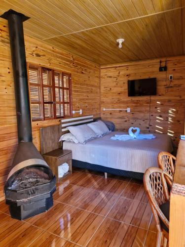 a bedroom with a bed and a fireplace in a cabin at Cabana Com Hidro e Lareira! Com Uma Linda Vista Para o Morro das Torres de Urupema in Rio Rufino