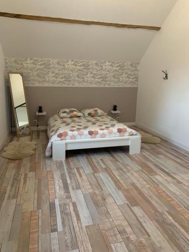 a bedroom with a bed and a wooden floor at Le Petit Moineau in Arthon