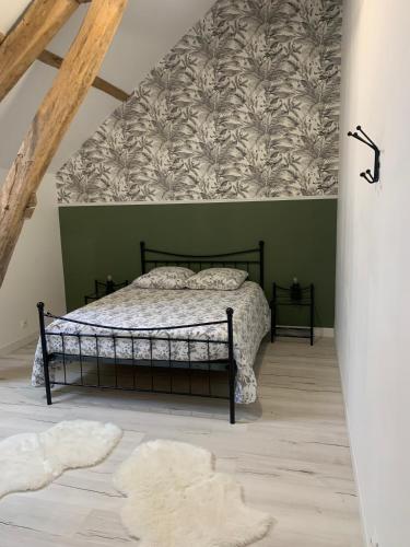 a bedroom with a bed and a green wall at Le Petit Moineau in Arthon