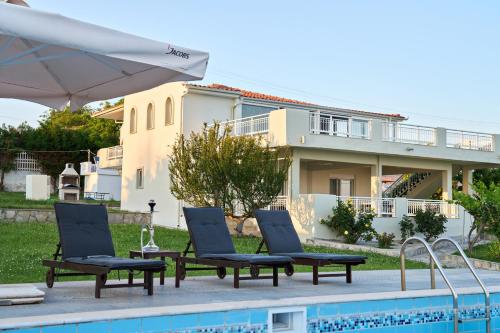 a swimming pool with two chairs and a house at Grand Villa Maronia in Platanitis Rodopis