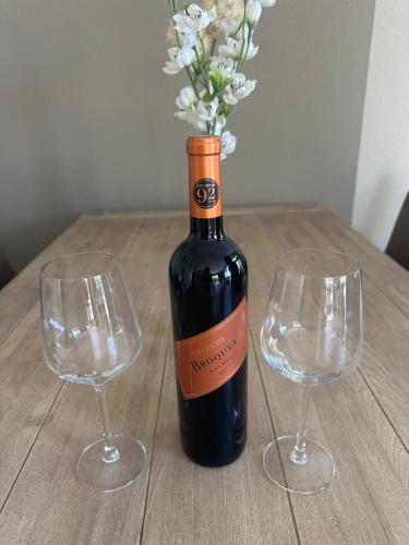 a bottle of wine and two wine glasses on a wooden table at Vakantiehuis Lemmer aan het water in Lemmer