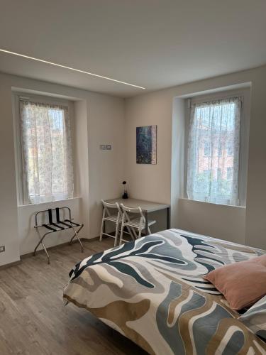 a bedroom with a bed and a desk and two windows at B&B Ersilia in Eupilio