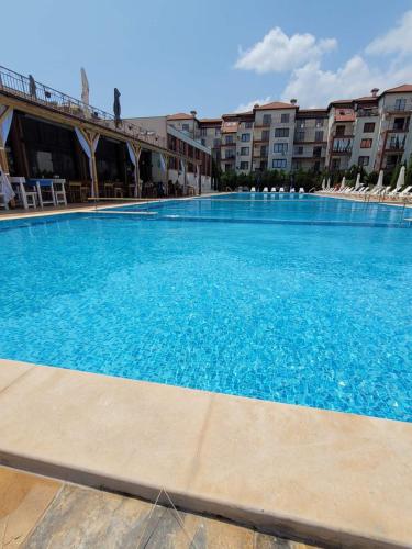a large blue swimming pool with chairs and buildings at Famagusta Antoniya in Aheloy