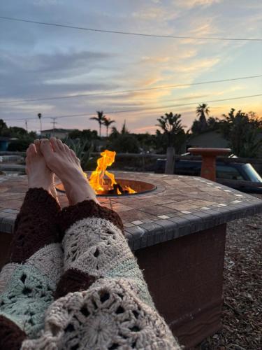 a woman laying in front of a fire pit at Seaside Garden Escape, A Stroll to the Beach! in Grover Beach