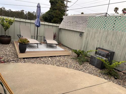 a patio with two chairs and an umbrella in a backyard at Seaside Garden Escape, A Stroll to the Beach! in Grover Beach