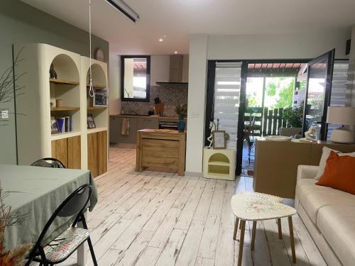 un salon avec un canapé et une cuisine dans l'établissement Appartement calme bord de forêt, à Lacanau-Océan