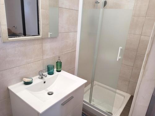 une salle de bain avec un lavabo blanc et une douche dans l'établissement CHARME 1850, climatisé et cinéma, à Montpellier