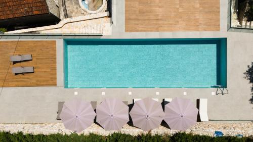 Una vista aérea de una piscina con tres sombrillas moradas. en GuestHouse Mrshe Palace, en Perast