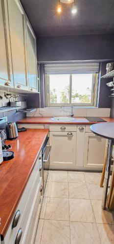 une cuisine avec des armoires blanches, un évier et une fenêtre dans l'établissement Cannes Côte d'Azur Sea View Air Conditioning Beach Apartment, à Cannes